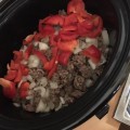 Adding beef onion and red capsicum to the slow cooker for beef chilli